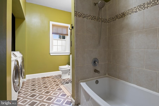 bathroom featuring toilet, baseboards, washing machine and clothes dryer, and shower / bathtub combination