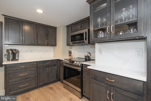 kitchen with glass insert cabinets, light countertops, stainless steel appliances, and dark brown cabinetry