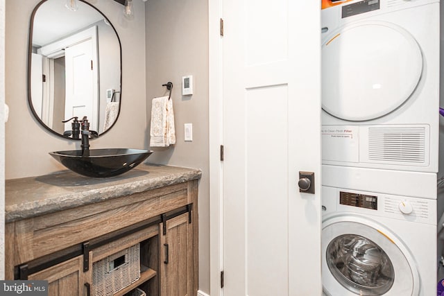 washroom featuring laundry area, stacked washing maching and dryer, and a sink