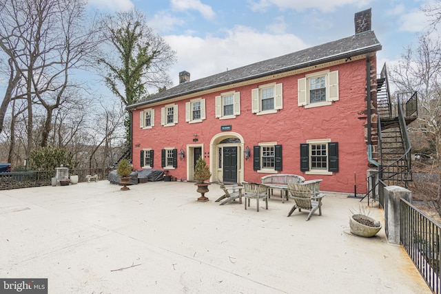 rear view of house featuring fence, a patio, a chimney, and stairs