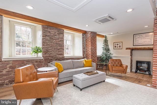 living area with a wood stove, a wainscoted wall, visible vents, and wood finished floors