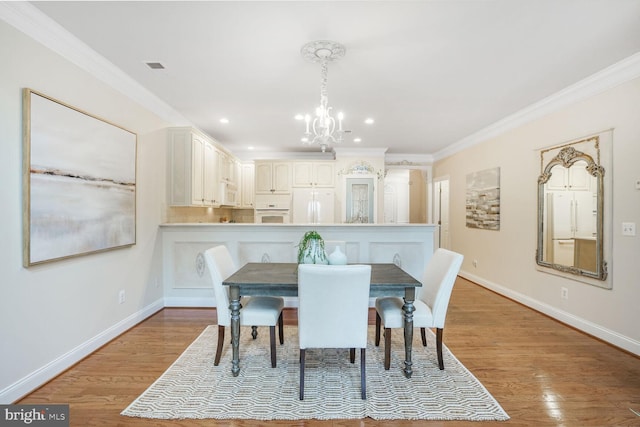 dining space featuring a chandelier, crown molding, baseboards, and wood finished floors