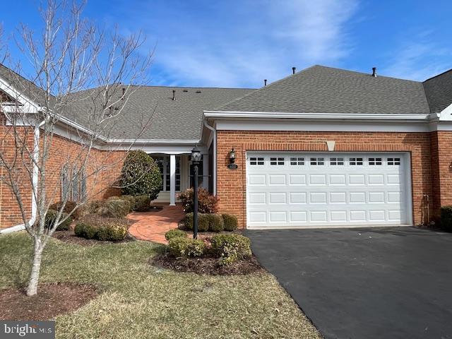 single story home featuring driveway, brick siding, an attached garage, and roof with shingles