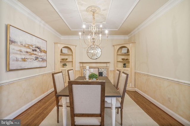 dining area featuring built in shelves, a chandelier, baseboards, and wood finished floors