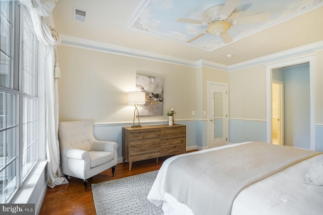 bedroom featuring wood finished floors, a ceiling fan, visible vents, a raised ceiling, and crown molding