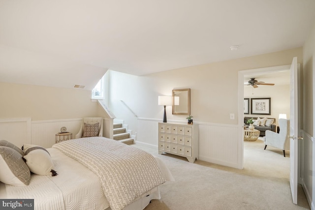 bedroom with a wainscoted wall, visible vents, and light colored carpet