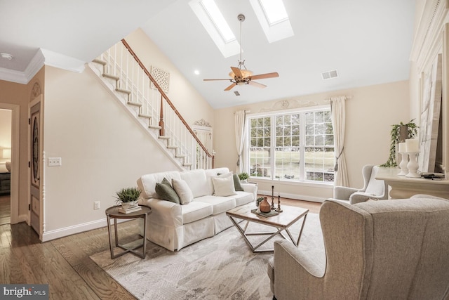 living area featuring a skylight, baseboards, visible vents, stairway, and wood finished floors