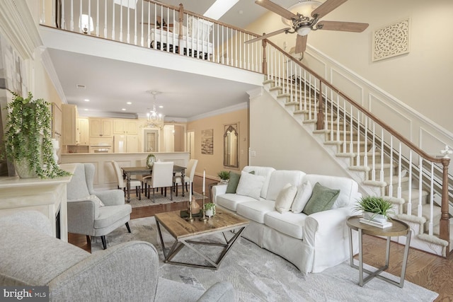 living room with light wood-style flooring, stairway, a high ceiling, crown molding, and a decorative wall