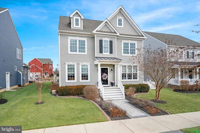 view of front facade with a shingled roof and a front yard