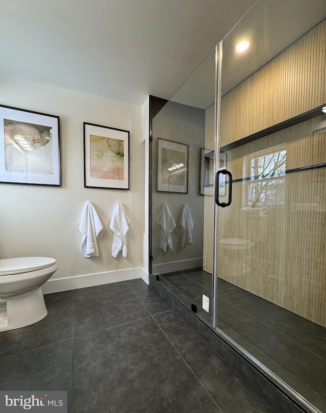 bathroom with toilet, a stall shower, tile patterned flooring, and baseboards