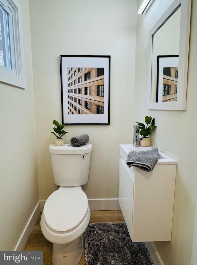 bathroom with wood finished floors, toilet, and baseboards