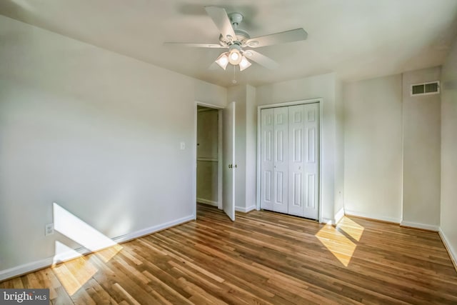 unfurnished bedroom featuring baseboards, a closet, visible vents, and wood finished floors