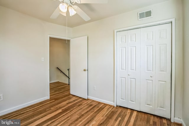 unfurnished bedroom with a closet, visible vents, baseboards, and wood finished floors