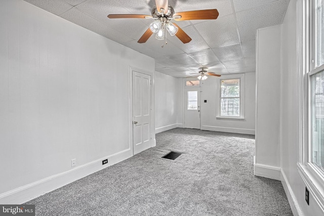 empty room with a paneled ceiling, visible vents, baseboards, and carpet flooring