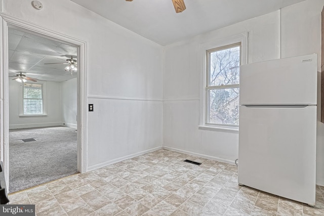 unfurnished dining area with visible vents, ceiling fan, light carpet, and baseboards