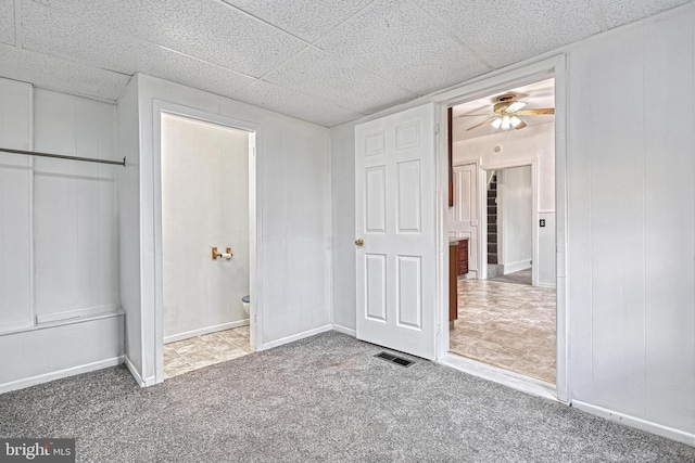 unfurnished bedroom featuring a drop ceiling, connected bathroom, carpet floors, visible vents, and baseboards