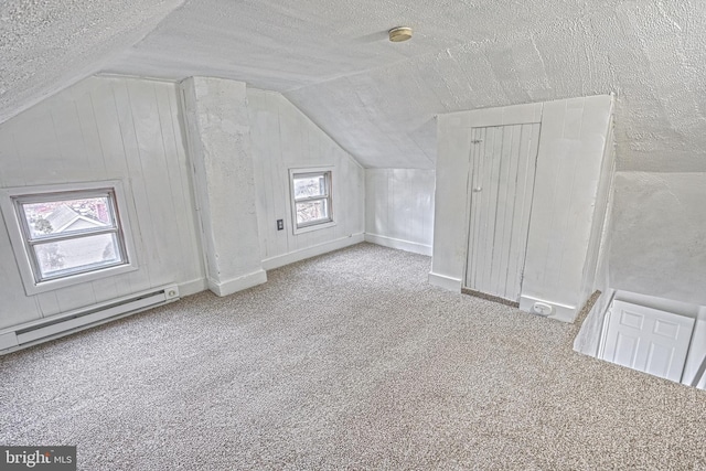 bonus room featuring a textured ceiling, lofted ceiling, a baseboard radiator, carpet floors, and baseboards