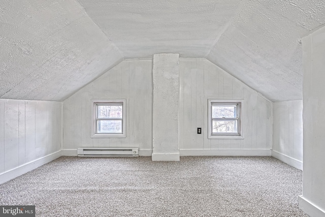 additional living space with carpet, a baseboard radiator, plenty of natural light, and a textured ceiling