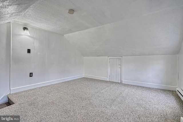 additional living space with carpet floors, baseboards, a textured ceiling, and lofted ceiling