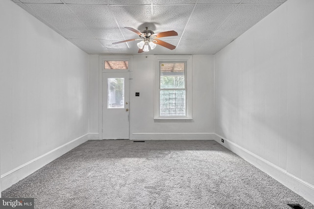 interior space featuring a ceiling fan, a drop ceiling, and baseboards