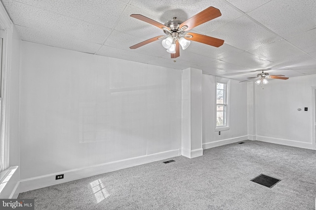 carpeted empty room with a paneled ceiling, visible vents, and baseboards