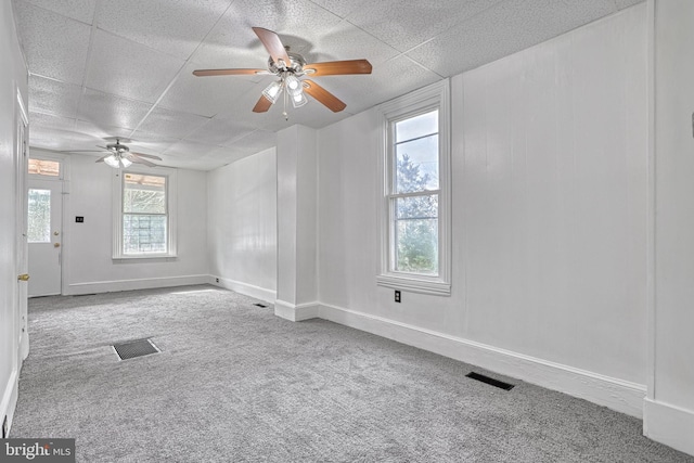 carpeted empty room with baseboards, visible vents, and a ceiling fan