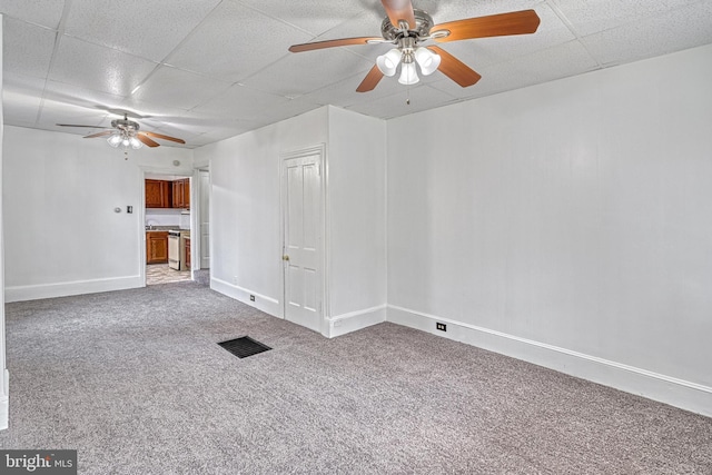 unfurnished living room with a paneled ceiling, visible vents, a ceiling fan, carpet flooring, and baseboards