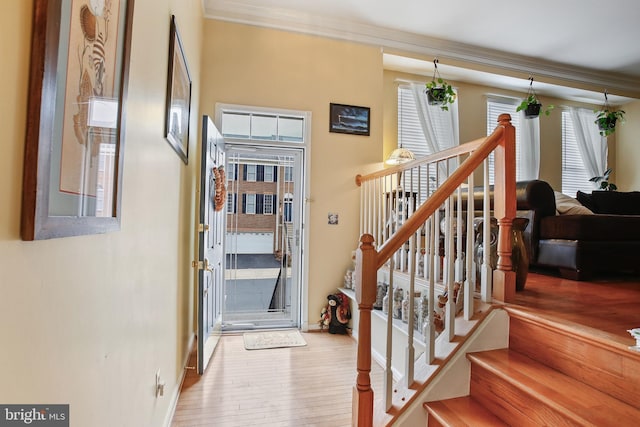 staircase featuring baseboards, wood finished floors, and ornamental molding