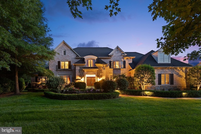 view of front of property with stone siding and a yard