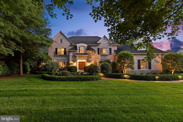 french country home featuring stone siding and a lawn