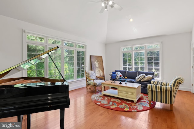 living room with lofted ceiling, ceiling fan, hardwood / wood-style flooring, and baseboards