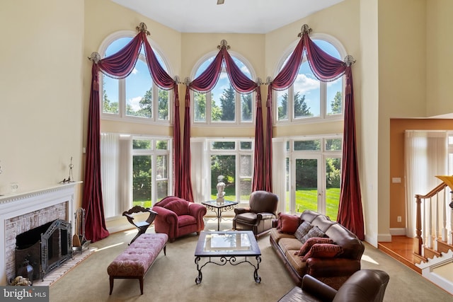 carpeted living area featuring baseboards, a fireplace, and a high ceiling