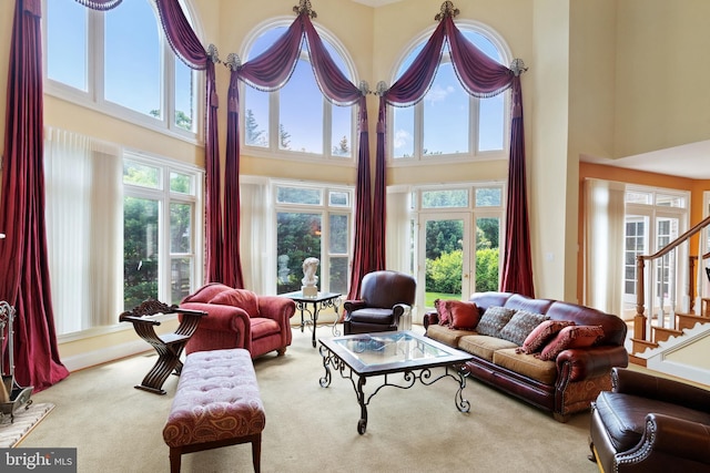 carpeted living room featuring plenty of natural light, a high ceiling, and stairs