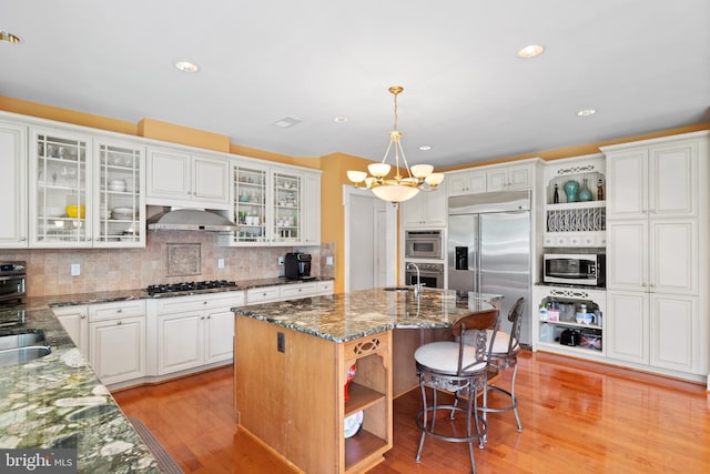 kitchen featuring appliances with stainless steel finishes, range hood, light wood finished floors, and open shelves