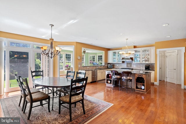 dining space with light wood-style floors and a notable chandelier