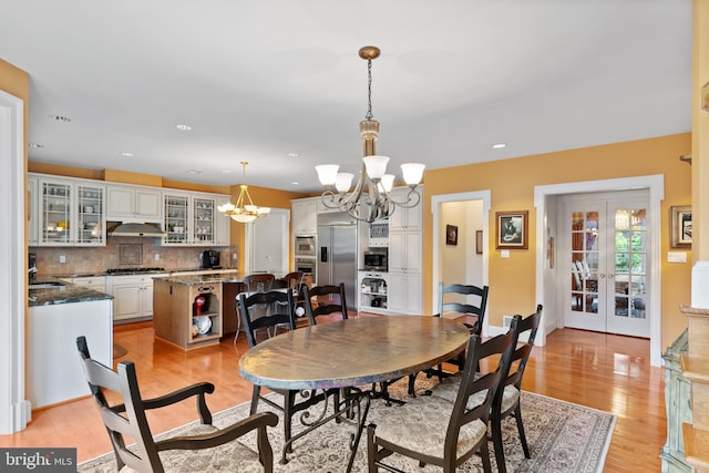 dining room featuring baseboards, french doors, light wood-style floors, a chandelier, and recessed lighting