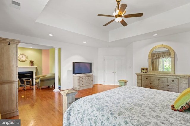 bedroom featuring a fireplace, recessed lighting, a raised ceiling, visible vents, and light wood-style floors