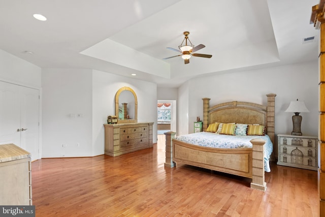 bedroom featuring light wood-style floors, visible vents, a raised ceiling, and recessed lighting