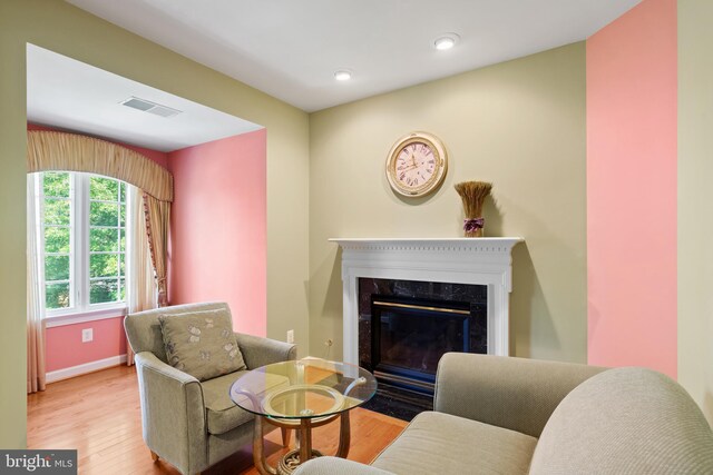 living room featuring a fireplace, wood finished floors, visible vents, and baseboards