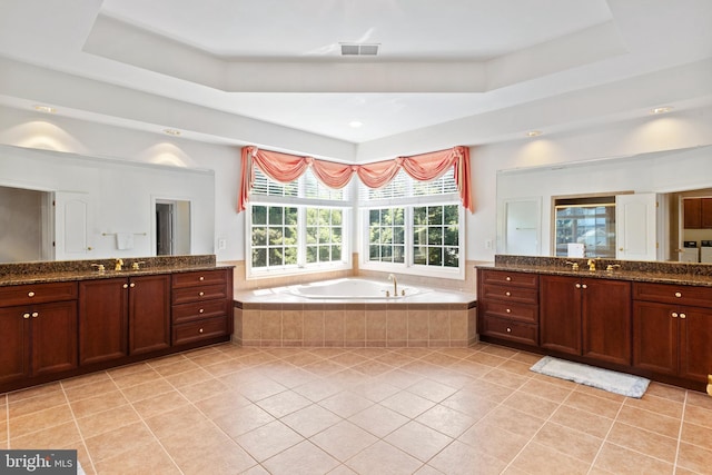 bathroom with tile patterned floors, a raised ceiling, a sink, and a bath