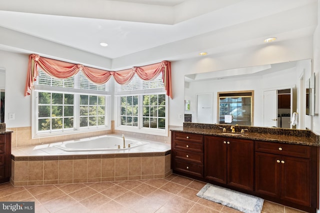 bathroom with a garden tub, vanity, and tile patterned floors