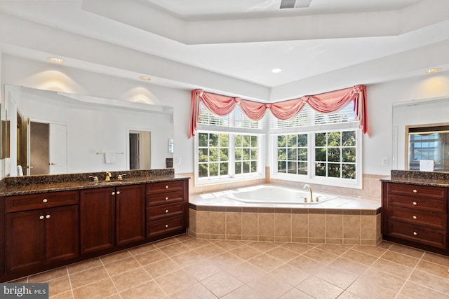 bathroom with tile patterned floors, vanity, a bath, and a healthy amount of sunlight