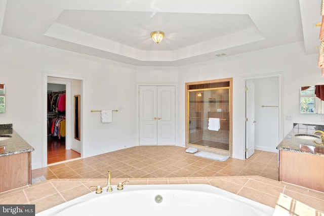 full bathroom featuring a stall shower, a tray ceiling, a bath, and vanity