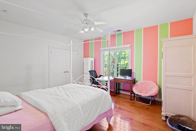 bedroom with wallpapered walls, visible vents, a ceiling fan, light wood-style flooring, and a closet