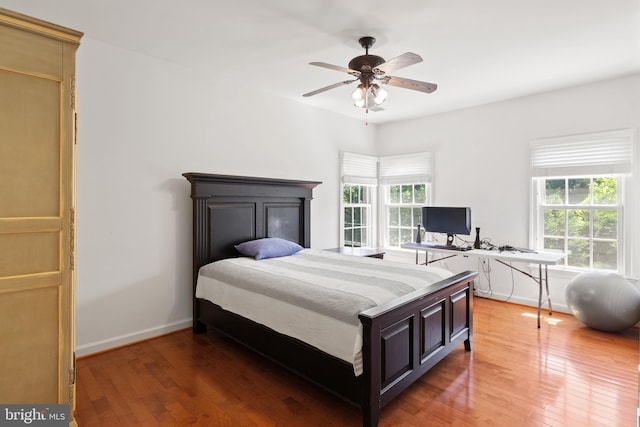 bedroom with a ceiling fan, light wood-style flooring, and baseboards