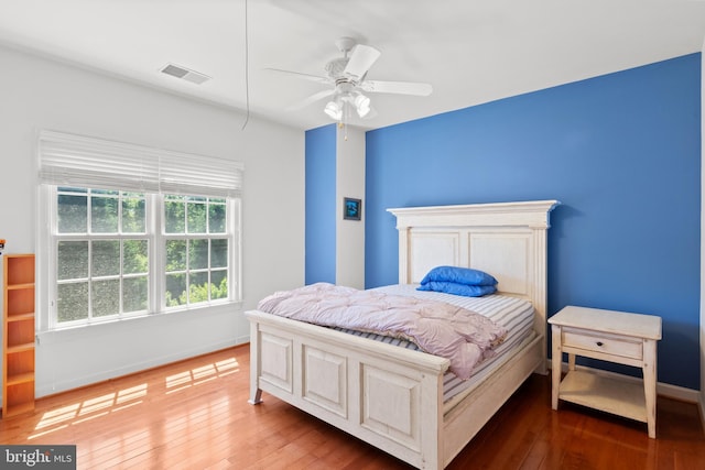 bedroom featuring ceiling fan, visible vents, baseboards, and hardwood / wood-style floors