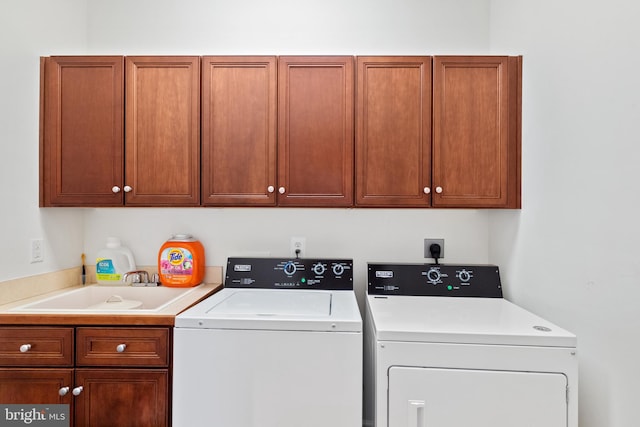 laundry room with cabinet space, separate washer and dryer, and a sink