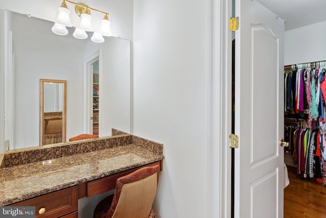 bathroom featuring wood finished floors, a walk in closet, and vanity