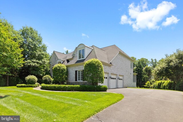 view of front facade featuring an attached garage, aphalt driveway, and a front yard