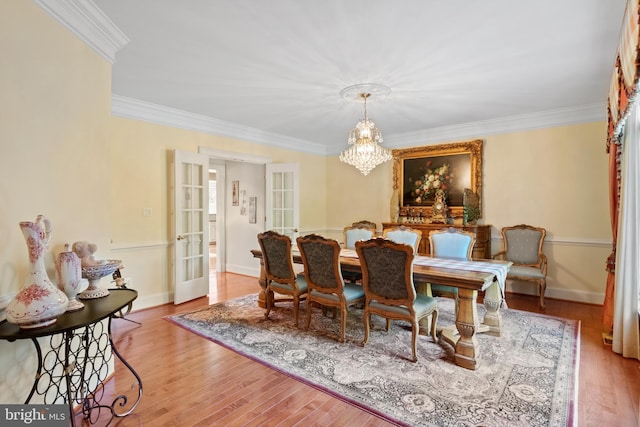 dining room featuring a chandelier, wood finished floors, baseboards, french doors, and ornamental molding